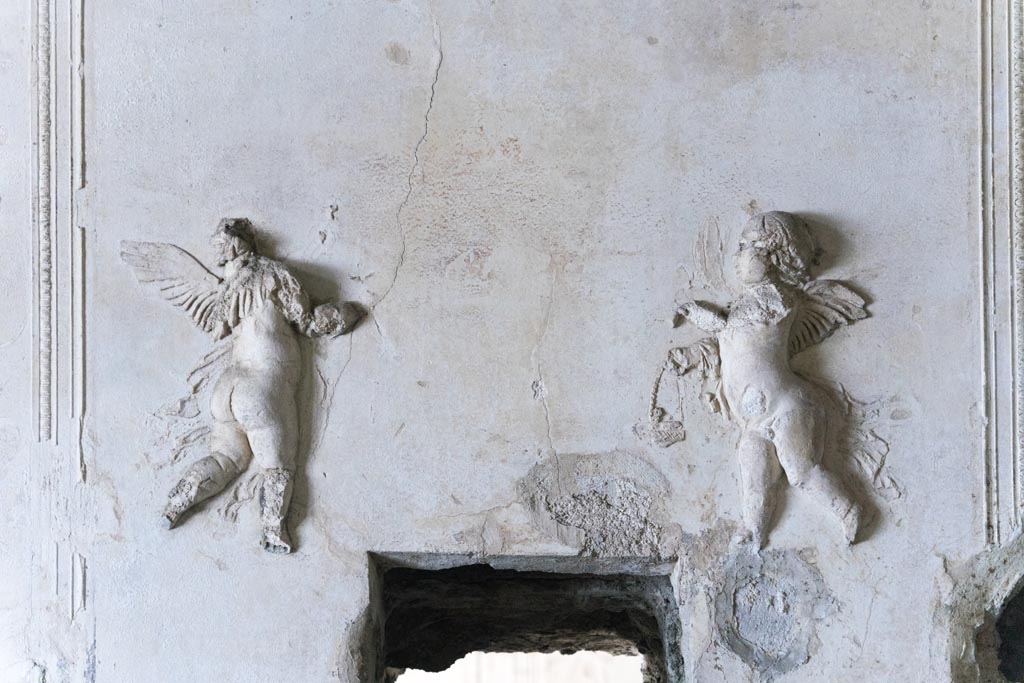 Herculaneum Suburban Baths. October 2023. Tepidarium, detail of stucco cupids from centre of west wall. Photo courtesy of Johannes Eber.